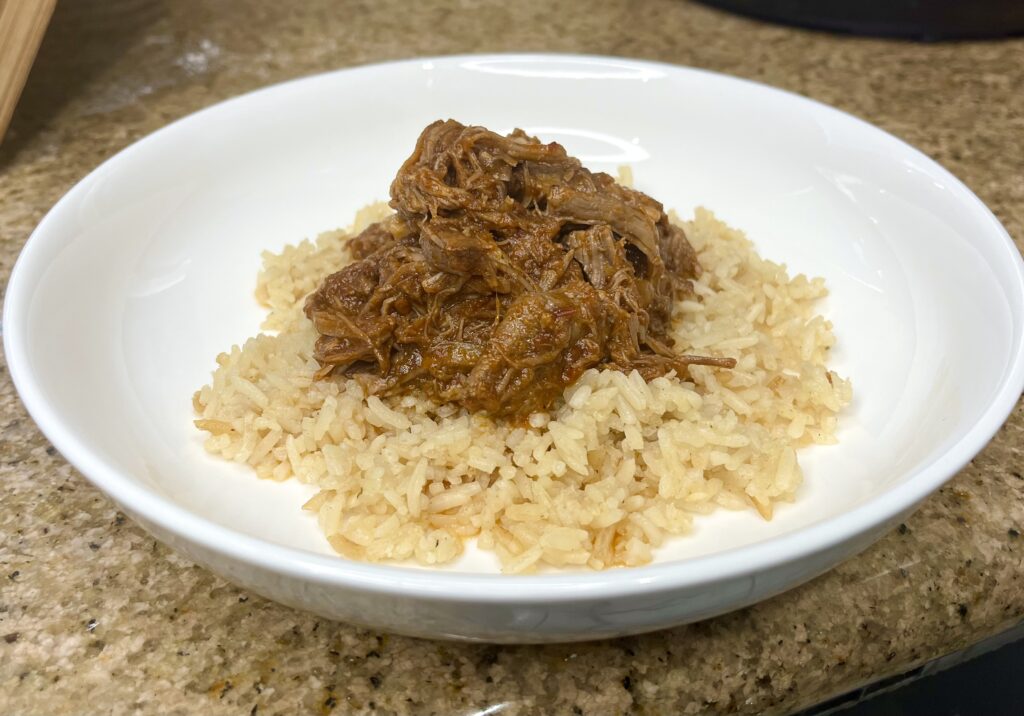 shredded chipotle chuck roast on top of a bed of rice on a plate