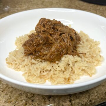 shredded chipotle chuck roast on top of a bed of rice on a plate
