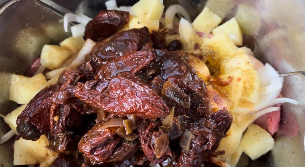 close up of chipotle peppers in adobo sauce on top of chopped pineapples