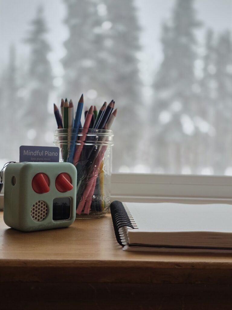yoto player, colored pencils and a sketchbook in a windowsill